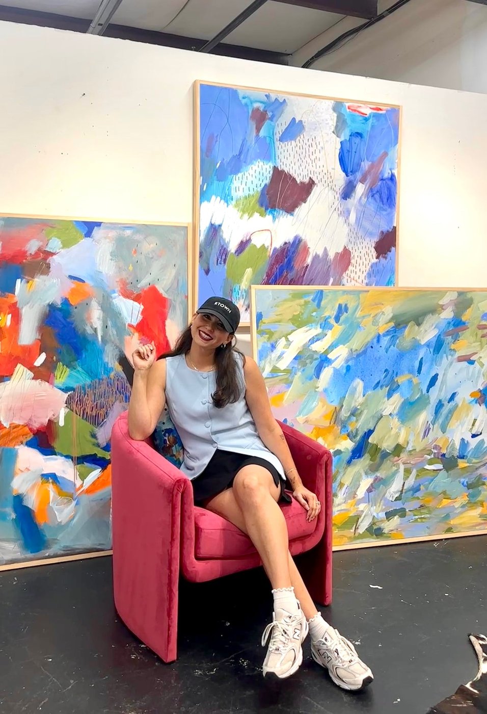 Rachel Townsend Cerny in her studio, seated in front of several large-scale mixed media paintings